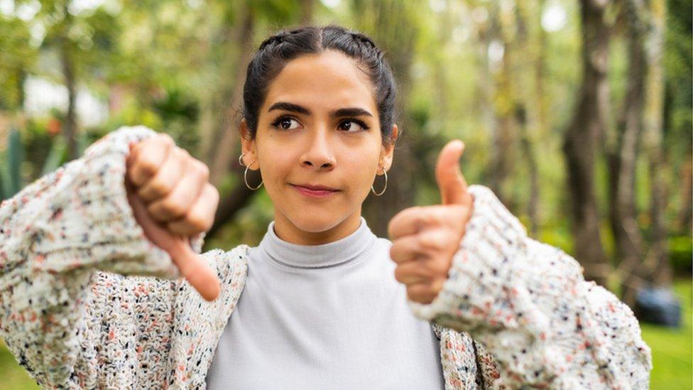 teenager holding thumbs up and thumbs down