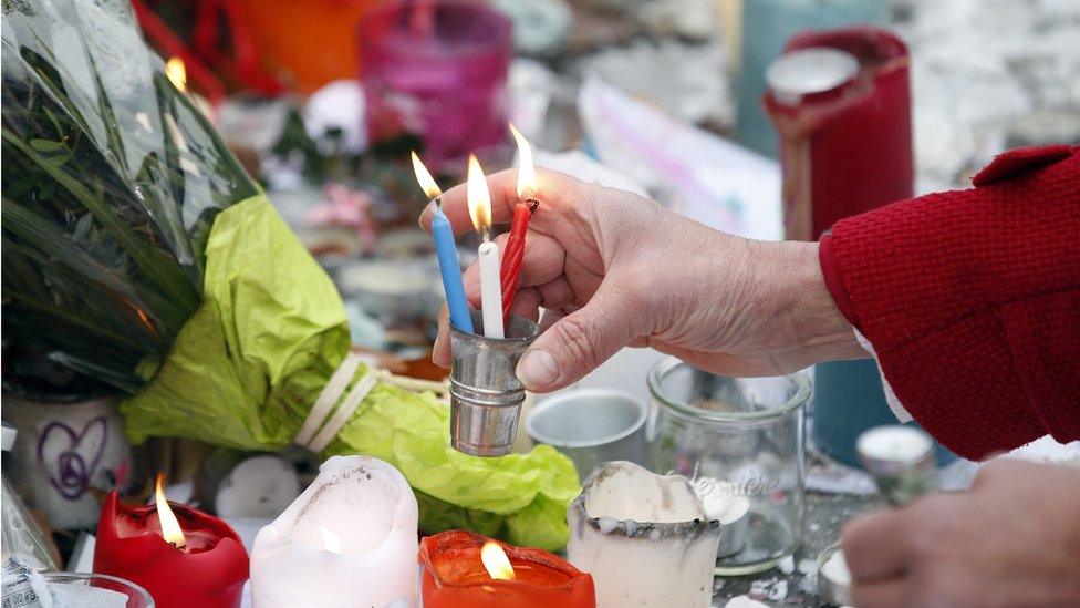 A woman sells candles in the colours of the French flag at the Place de la Republique