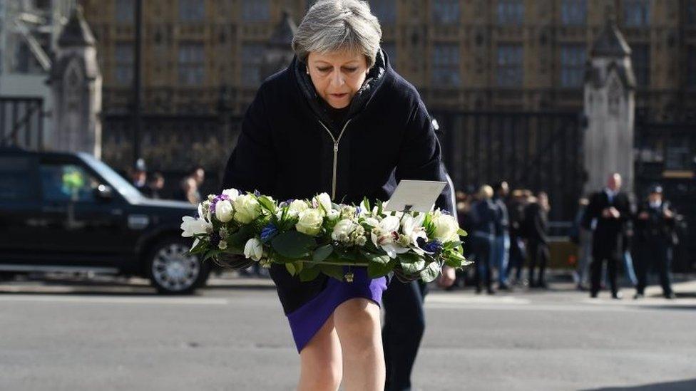 Theresa May has laid a floral tribute outside parliament