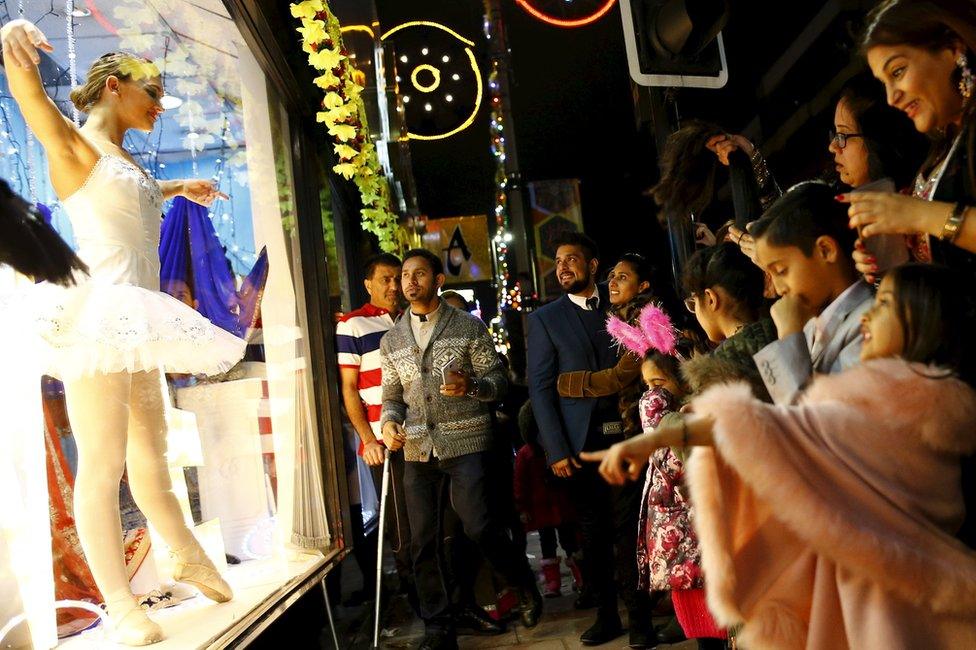 People watch a ballerina dance in a shop window during Diwali celebrations in Leicester