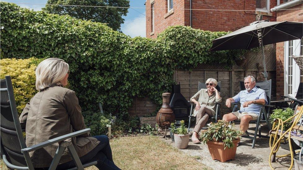 Parents and their daughter socially distant in the garden.