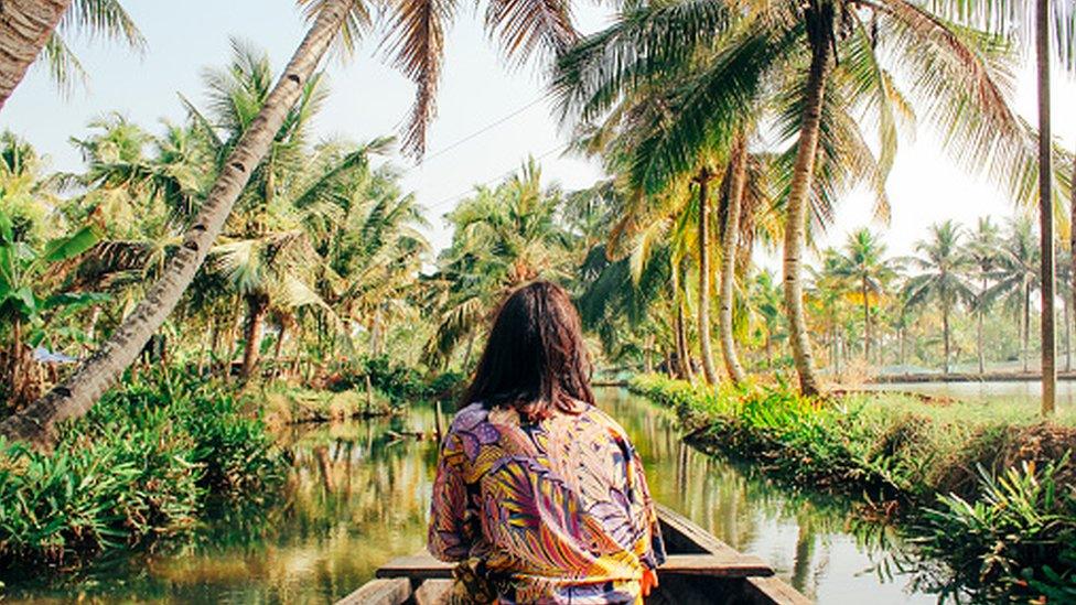 A young woman kayaks through the backwaters of Monroe Island in Kollam District, Kerala, South India.