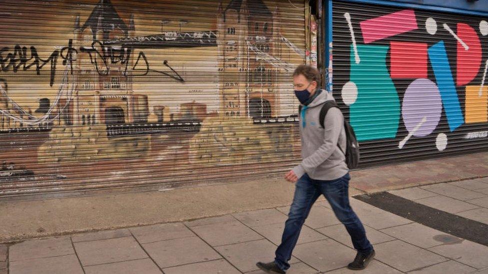 Man walking by shuttered shops