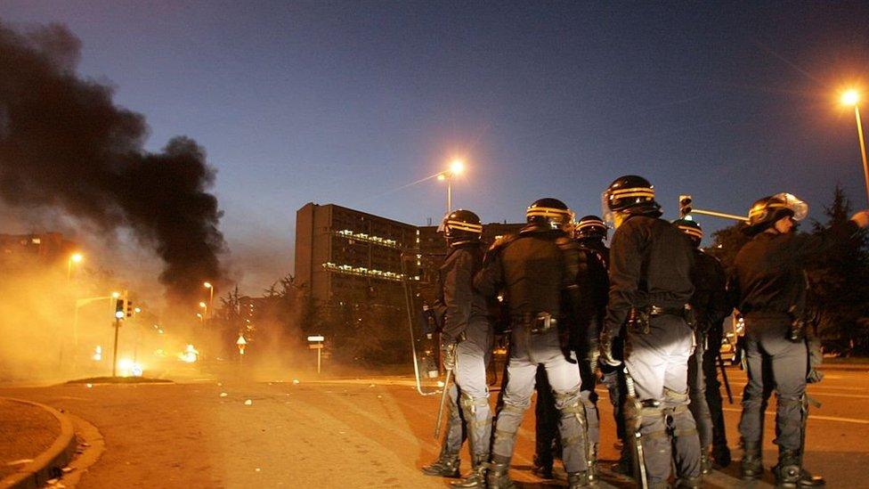 Policemen stand guard as a bus is burning in an estate in Toulouse, November 2005