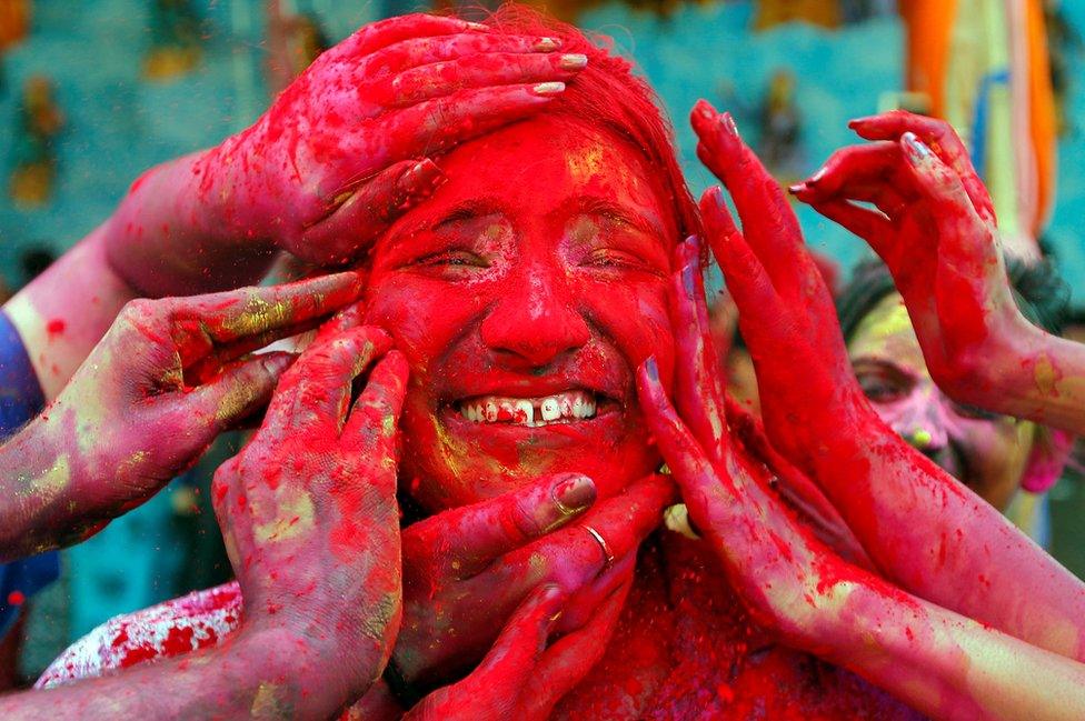 A woman reacts as devotees apply coloured powder on her face during celebrations for Holi outside a temple on the outskirts of Kolkata, India, 21 March 2019.