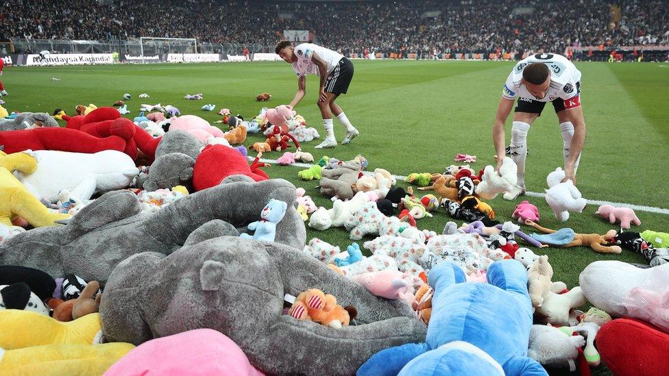Fans of Besiktas throw Teddy bears onto the field in support for the earthquake victim children