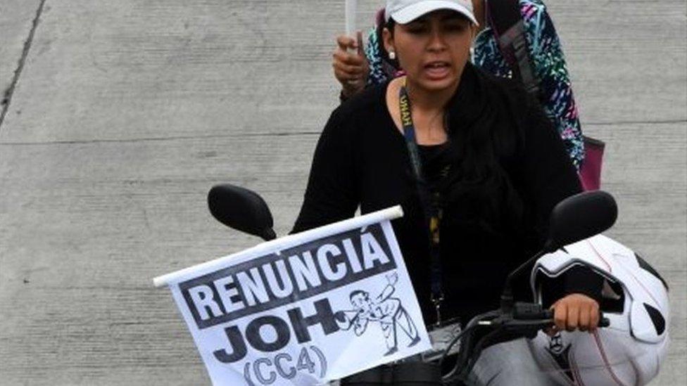 Protesters on a motorbike hold up placards reading "resign JOH (CC4)