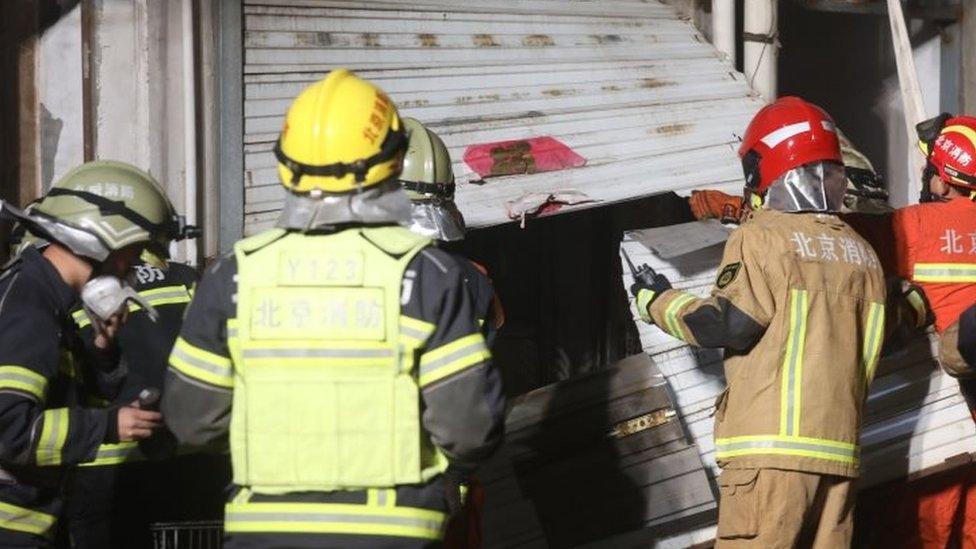 Chinese firemen gathering around a house where a fire tore through it, in Beijing (19 November 2017)