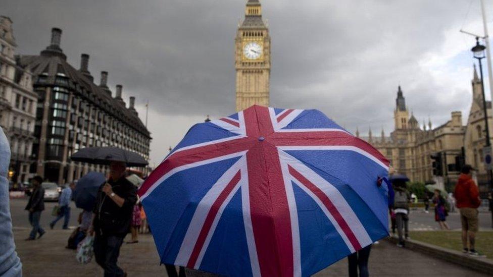 A pedestrian shelters from the rain beneath a Union flag themed umbrella in London. File photo