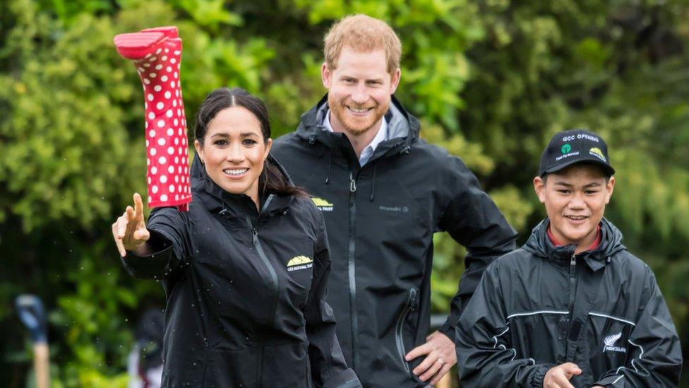 Prince Harry and Meghan, the Duchess of Sussex, throw wellies outside.