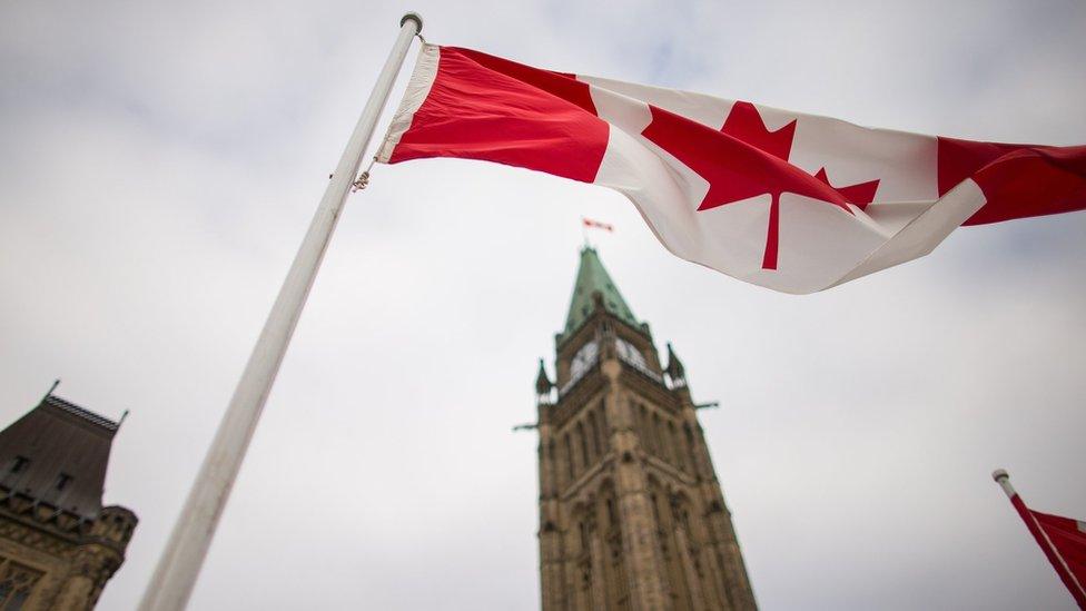 A Canadian flag flies in front of the peace tower on Parliament Hill in Ottawa, Canada on December 4, 2015