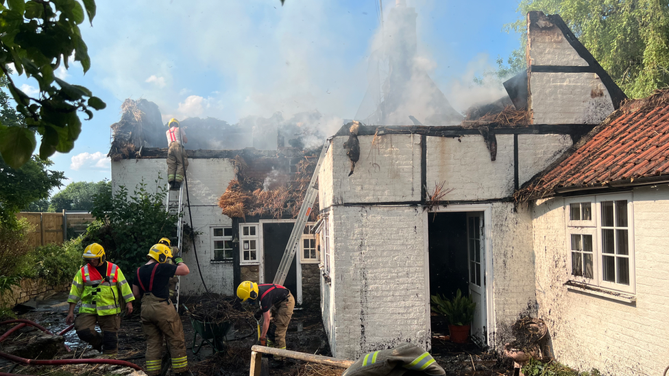 A fire in thatched roof of house in Urchfont with firefighters in action