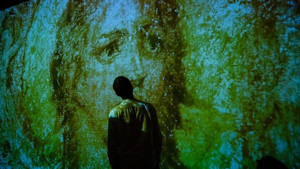 A visitor to Tate Britain standing in front of a William Blake projection