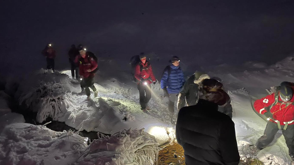 Rescuers walk through snow