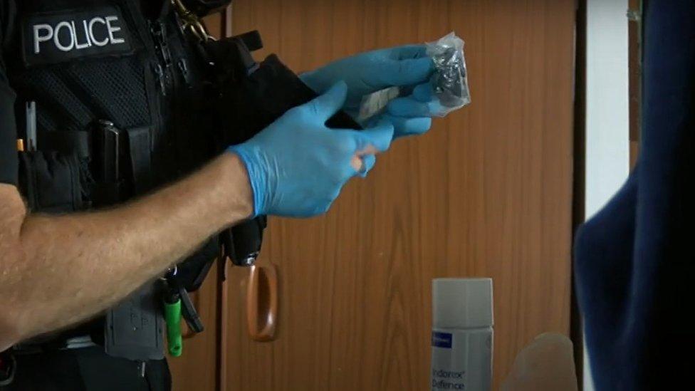 Police officer wearing blue gloves and holding suspected drugs