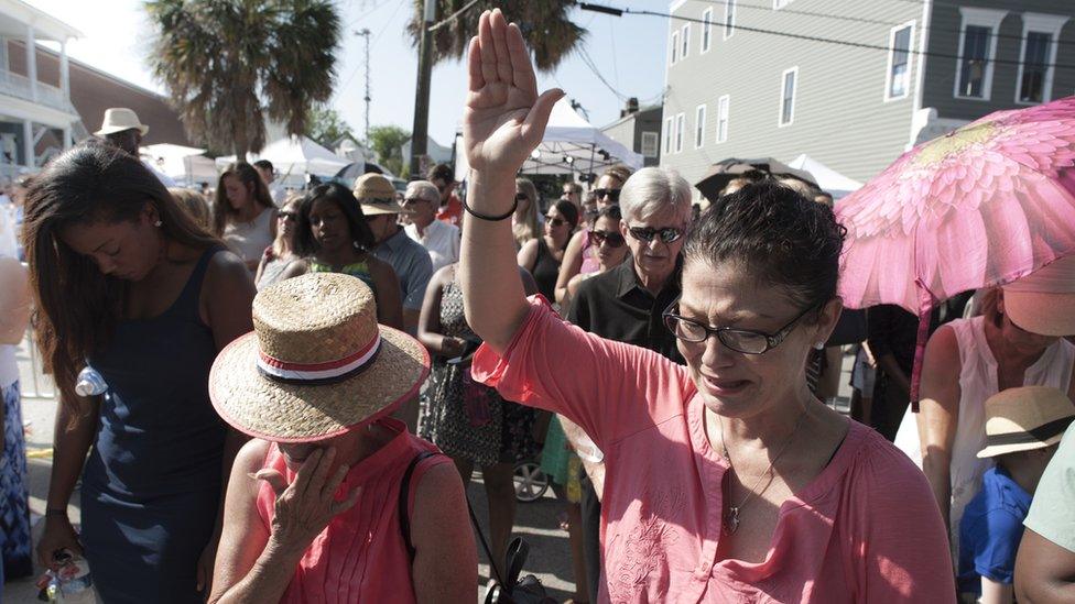 2015-06-21. Members of the community gathered in front of Emanuel AME Church in Charleston Sunday. Colm O'Molloy for BBC News.