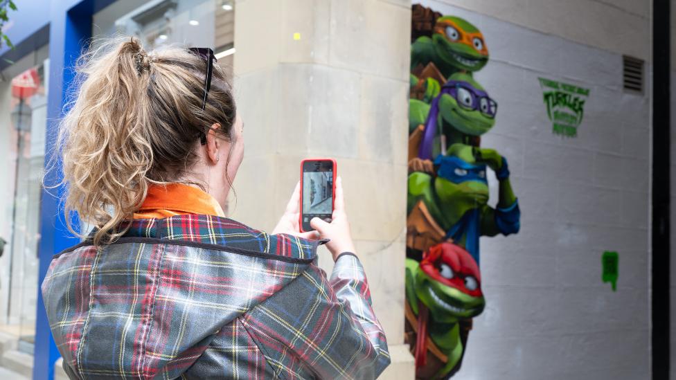 A general view of the public photographing street art depicting the Teenage Mutant Ninja Turtles on July 26, 2023 in Manchester, England.