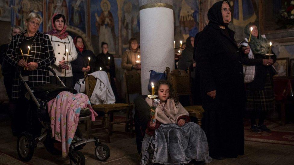 A young girl closes her eyes as she and other Serbian Orthodox Christians hold candles during a midnight Easter service at a monastery in the village of Sukovo