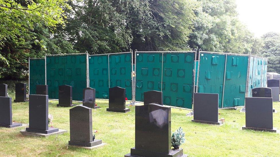 Large screens in a graveyard - hiding the exhumation process