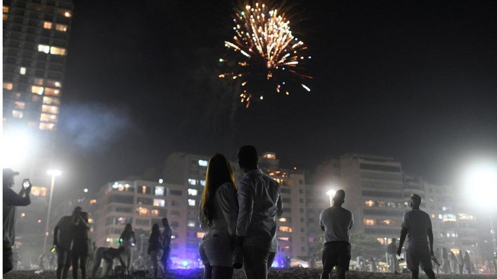 People on beach in Brazil watch fireworks