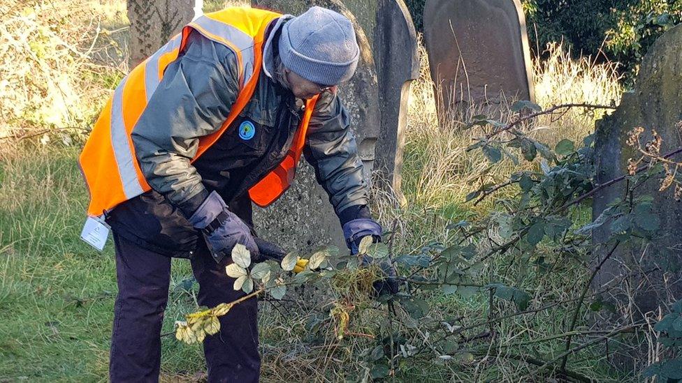 A person tending a grave in Mill Road Cemetery in Cambridge