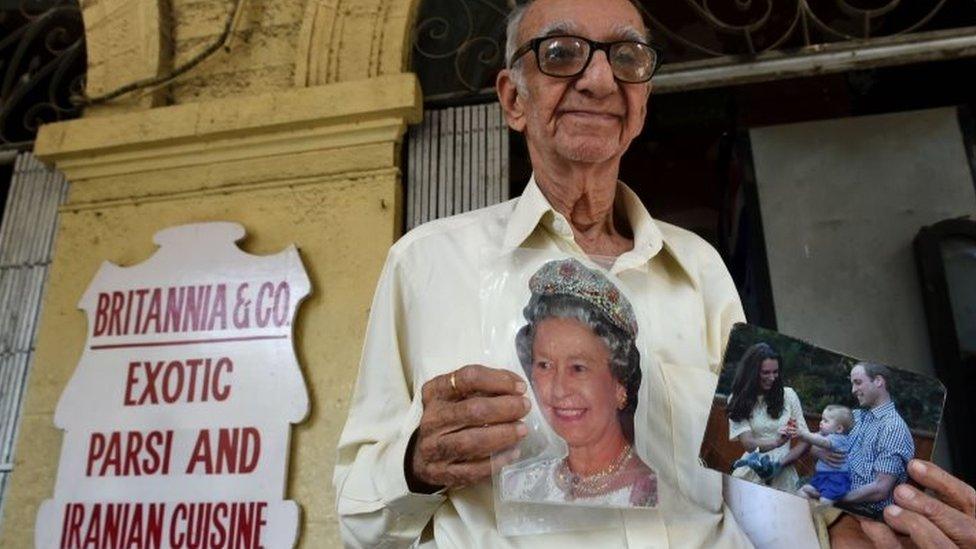 Indian restaurateur Boman Kohinoor, 93, an ardent fan of the British royal family, poses with photos of Queen Elizabeth, and the Duke and Duchess of Cambridge outside the Britannia Co. restaurant in Mumbai (08 April 2016)