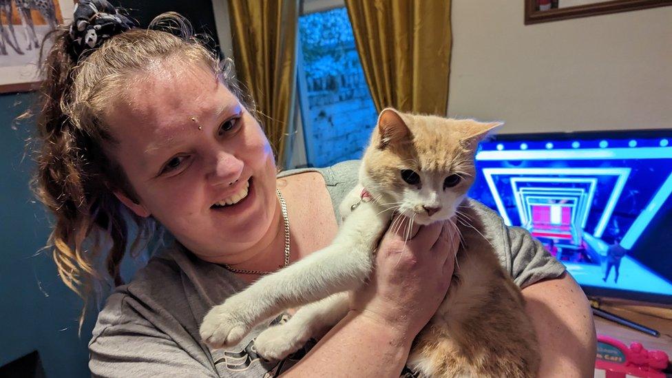 Woman holds white and ginger cat