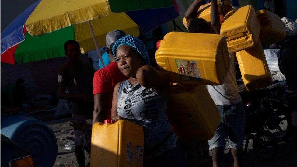 Locals carry containers, used for oil and gasoline, during fuel shortages in Port-au-Prince, Haiti October 24, 2021