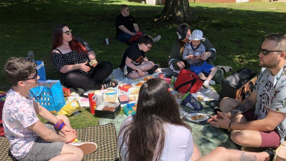 People sitting on picnic blankets with food spread around them