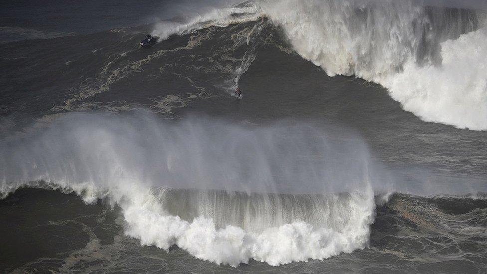 A surfer rides a wave in Praia do Norte, Nazaré, Portugal, in February 2022