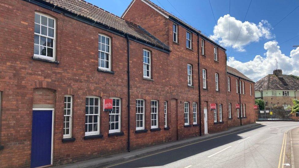 A photorealistic illustration showing the former police station as new houses