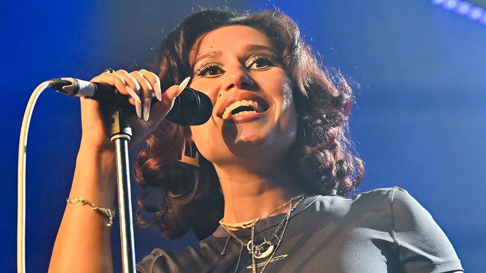 Head and shoulders shot of Raye singing into microphone in London in January