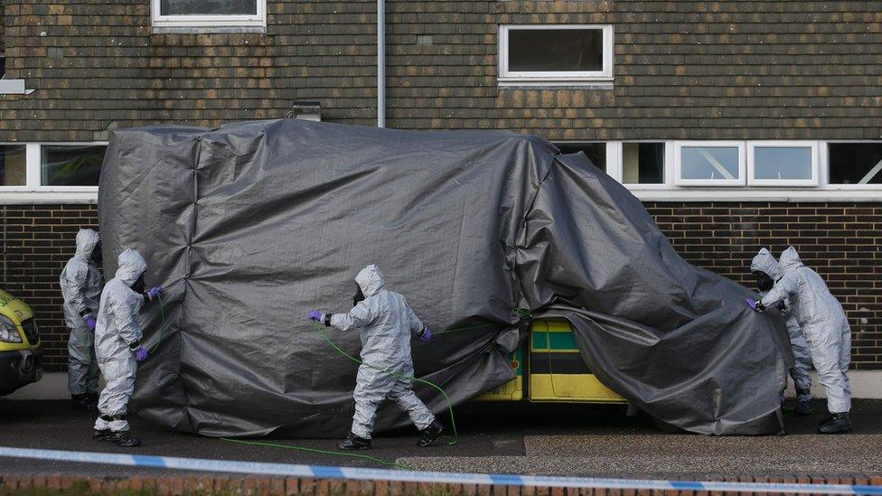 Troops cover an ambulance with a tarpaulin