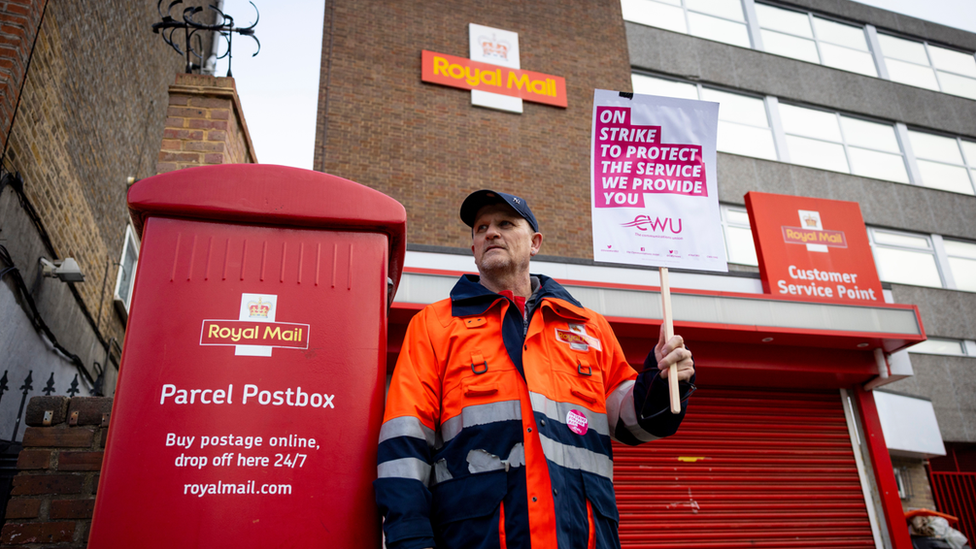 A Royal Mail worker seen holding a placard while on strike outside a depot