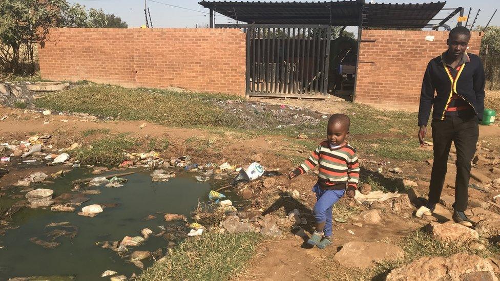 Residents walk pass a broken sewerage pump station in Reagile township, Koster