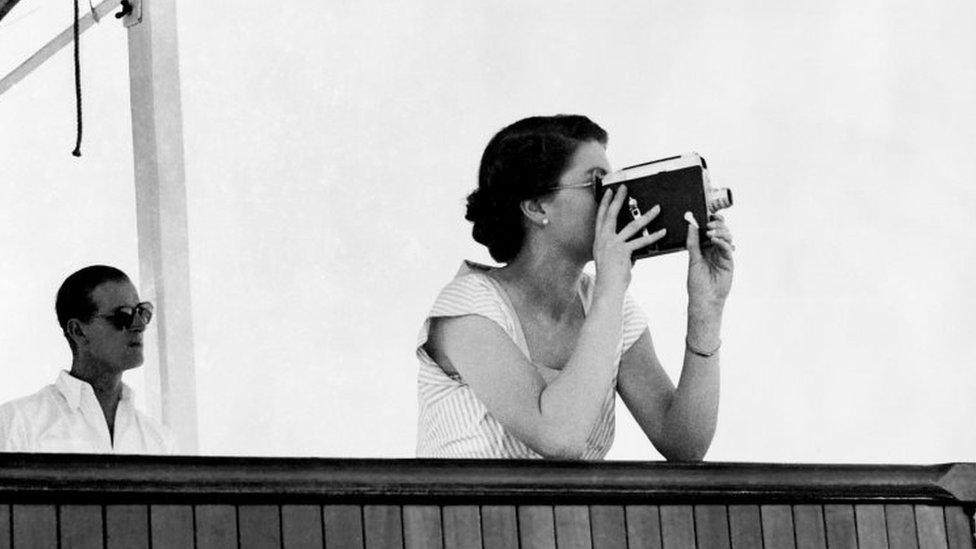 The Queen taking a cine-film in 1953 of a cruiser ship, the HMS Sheffield