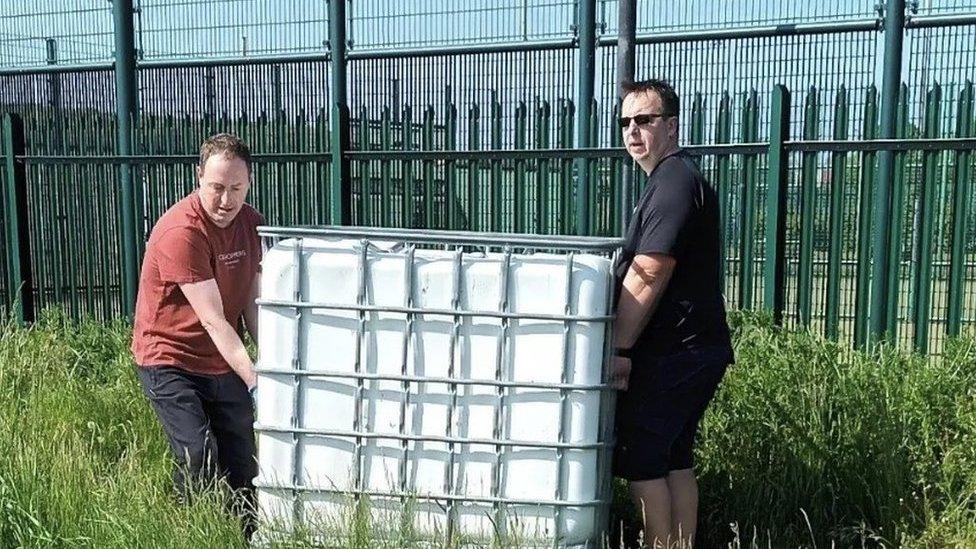 Volunteers at Cotgrave Community Garden next to a water tank