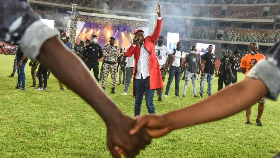 Ivorian reggae singer Alpha Blondy (C) performs during a concert in homage to late Ivory Coast Prime Minister Hamed Bakayoko at the Ebimpe Olympic Stadium in Anyama, Abidjan, on March 17, 2021. - Ivory Coast's Prime Minister Hamed Bakayoko, a popular leader who reached across the political spectrum as the divided West African country seeks reconciliation, died aged 56 on March 10, 2021, following cancer treatment in a German hospital. Bakayoko, popularly known as "Hambak", died four days after legislative elections that went ahead peacefully and handed victory to the ruling RHDP party.