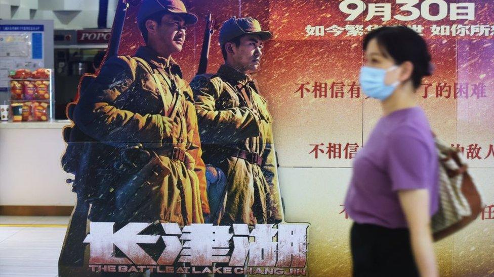 A movie-goer walks by a poster for the blockbuster The Battle at Lake Changjin at a cinema in Hangzhou