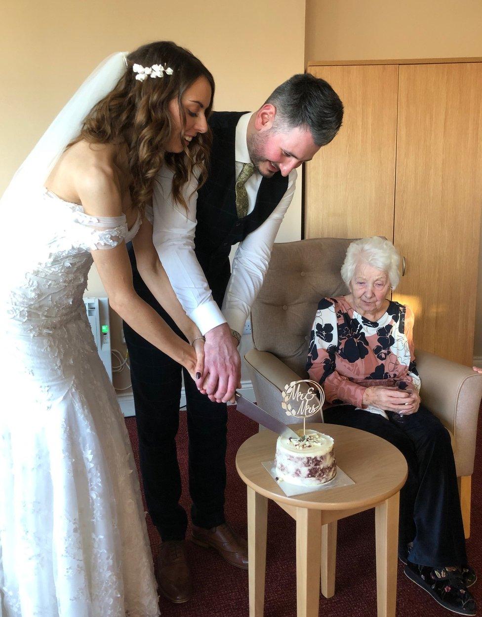 Hannah and Jay cut a cake as Liz Jobey looks on