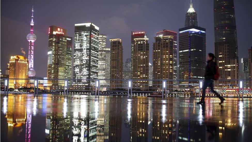 A woman walks at the Bund in front of the financial district of Pudong in Shanghai in this 5 March 2015 file picture