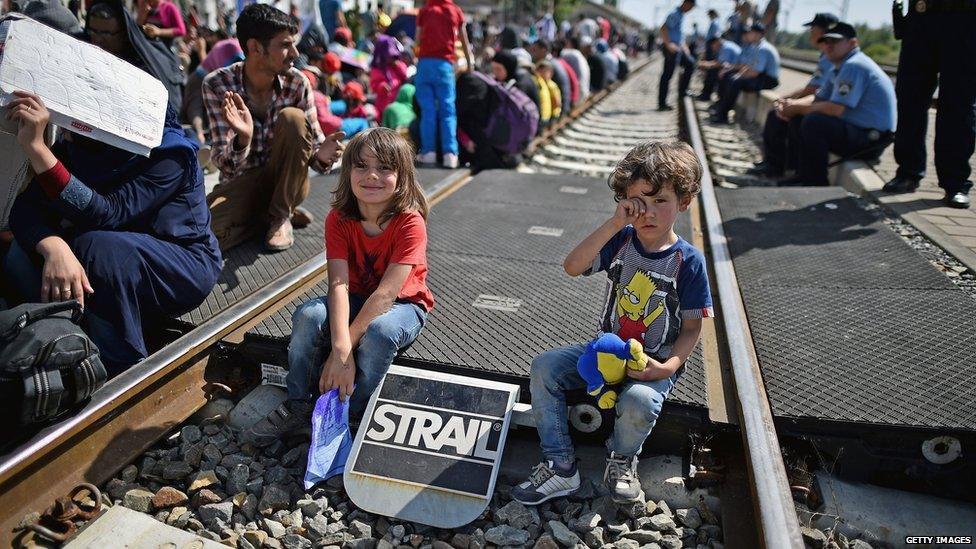 Two children sit on the tracks as hundreds of migrants wait at Tovarnik station for a train to take them to Zagreb on September 17, 2015 in Tovarnik, Croatia