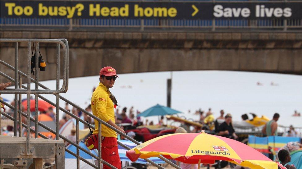 An RNLI Lifeguard patrols Boscombe beach in Dorset