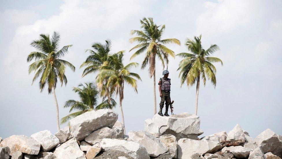 A policeman stands guard atop rocks overlooking the proposed Dangote oil refinery site during a facility tour near Akodo beach in the outskirt of Nigeria's commercial capital Lagos June 25, 2016.