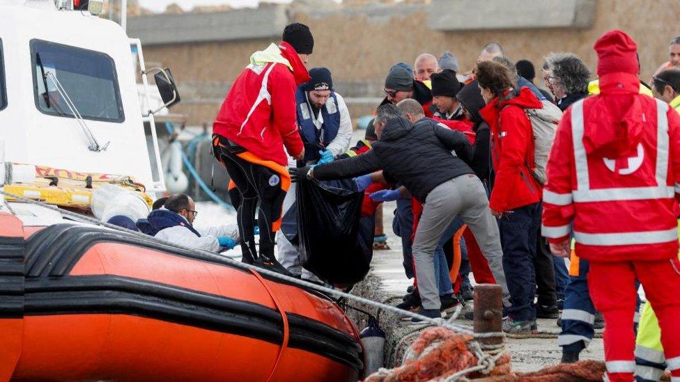 A coast guard boat offloads to a dock