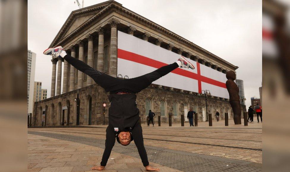 Joe Fraser doing a handstand in front of the flag