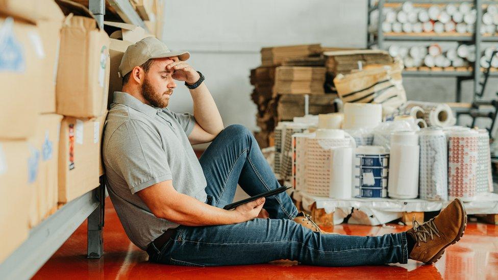 A stock photo of a tired warehouse worker