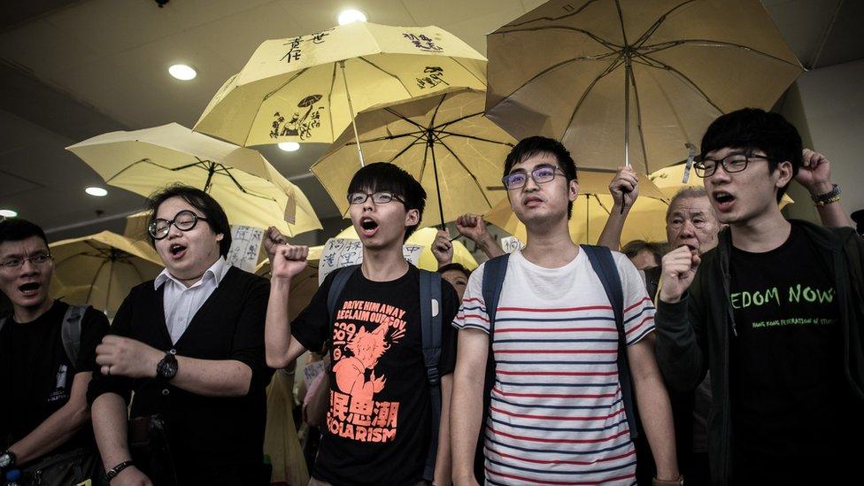 Student protesters Joshua Wong (C), Alex Show (2nd L) and Nathan Law (R) shout slogans outside a court of justice in Hong Kong on September 2, 2015