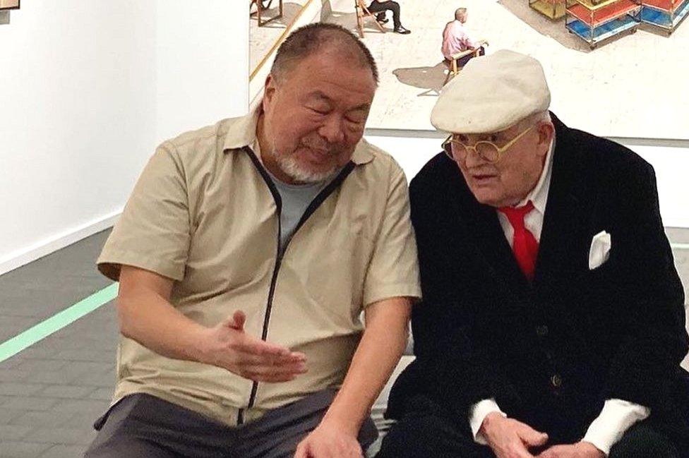 Artists Ai Weiwei and David Hockney sitting in a museum