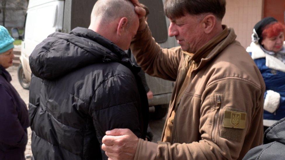 A Ukrainian pastor with his hand on a man's head